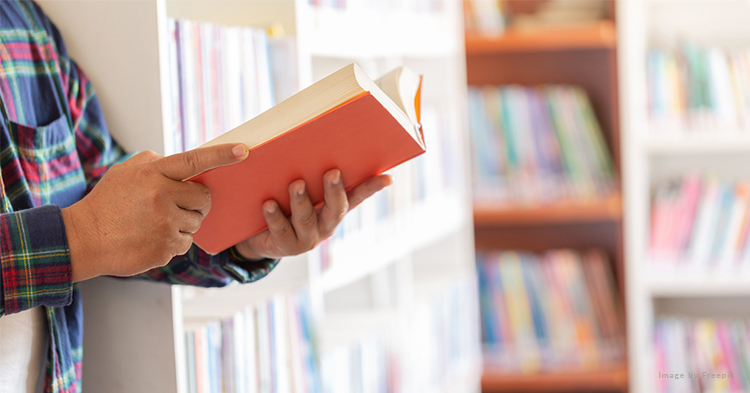 A person holding a book in a library