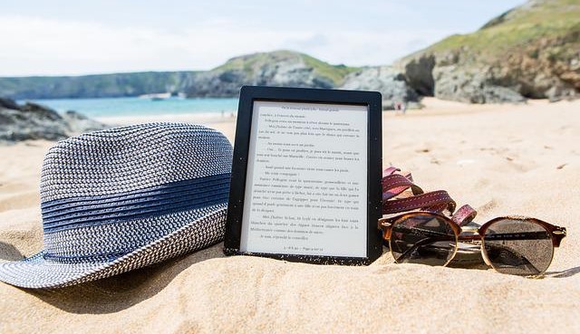 Ebook, hat and sunglasses on a beach