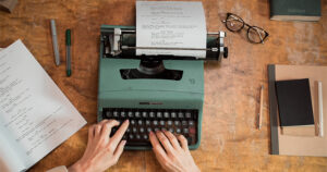 A person writing on a typewriter preparing his manuscript for 2024 writing contests