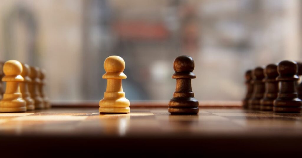 Two chess pawns of opposite colors representing conflict