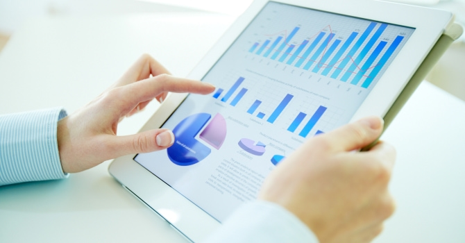 A person looking at data analytics on a tablet against a pale, white backdrop.