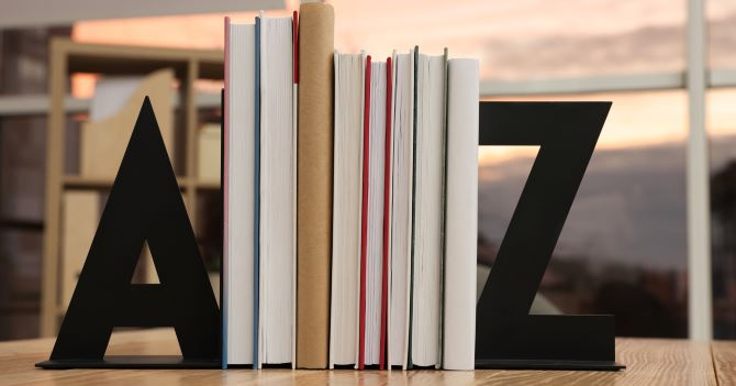 A shelf of books standing vertically in a book stand, which is shaped like an "A" on the left and a "Z" on the right.