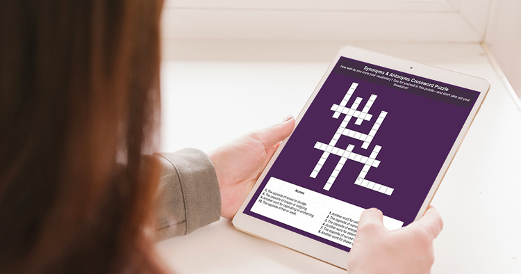 A little girl holding a tablet with an open crossword puzzle in education setting.