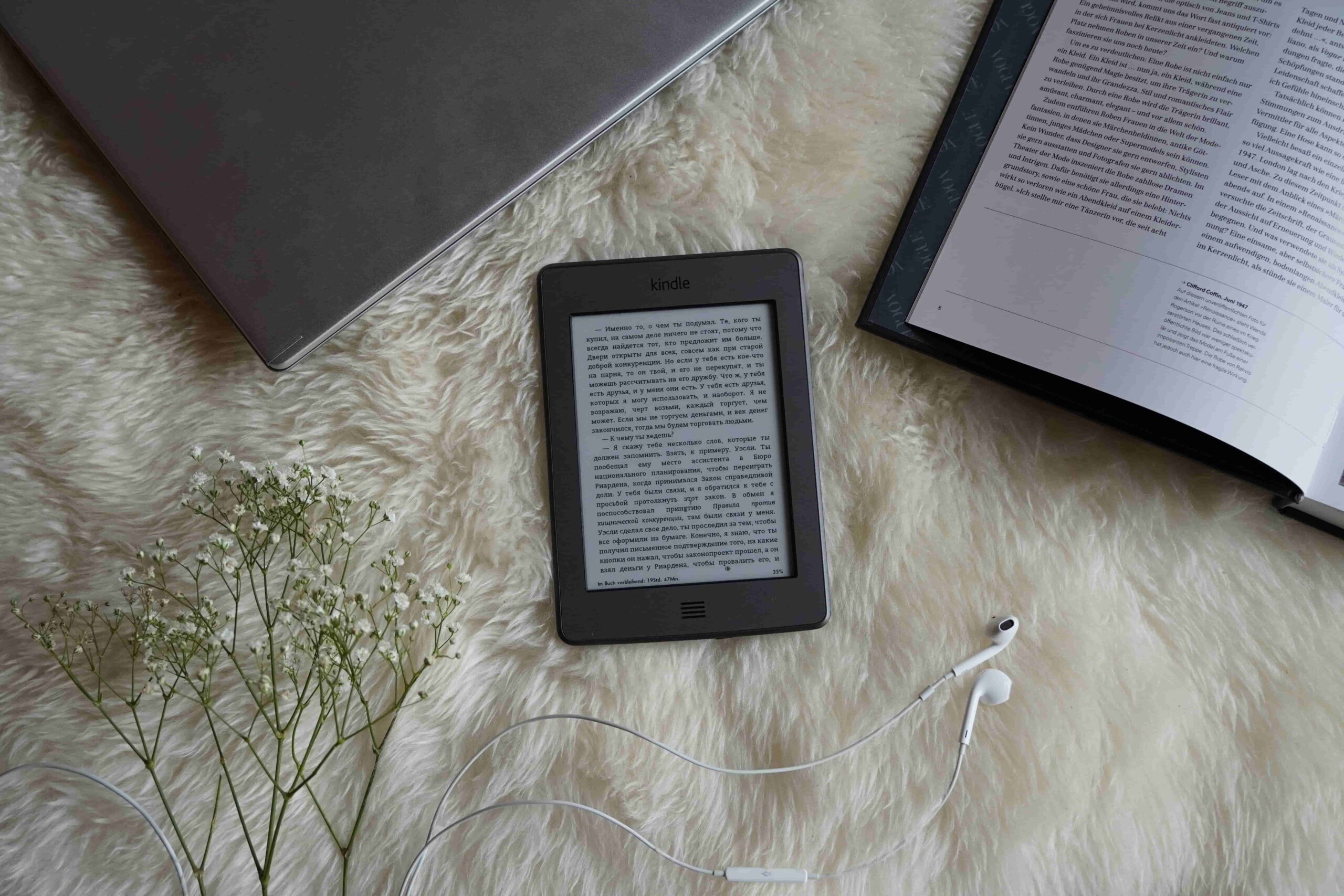 E-reader on the rug with lapop and book around it